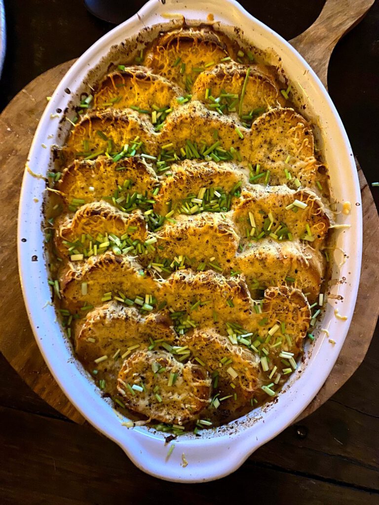 Versgebakken hartige ovenschotel met brood, kaas en verse bieslook — een liefdevol bereid gerecht tijdens de retreats in de Algarve.